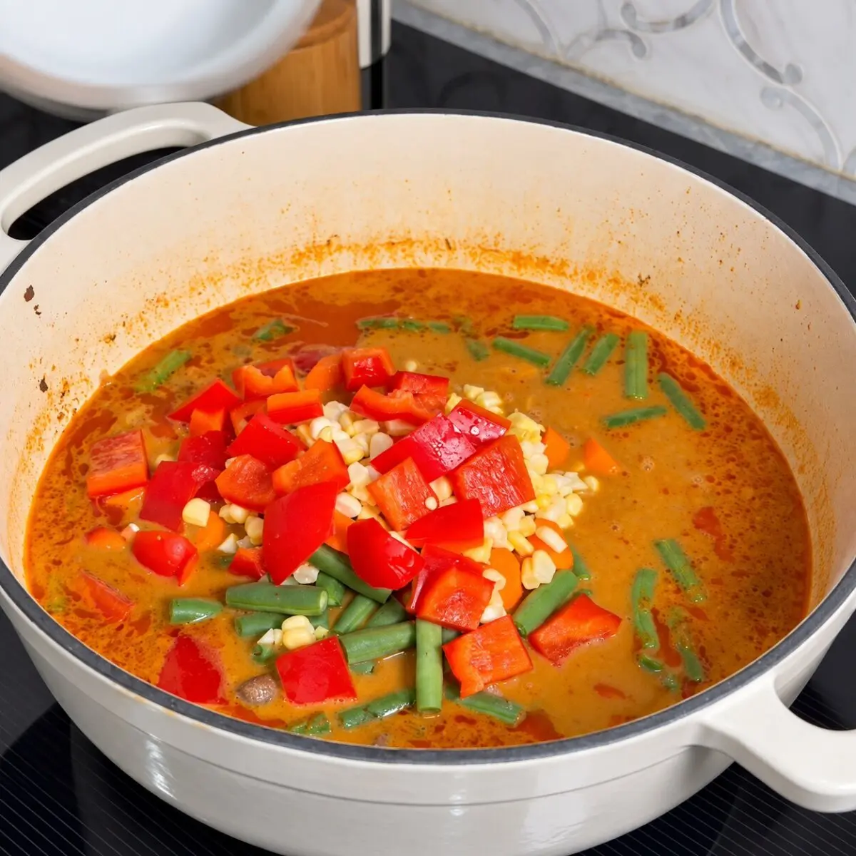 Carrots, green beans, red bell pepper and corn added to beef rendang vegetable soup.