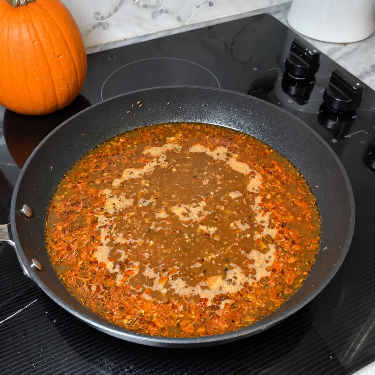 Stock and aromatics reducing in a black skillet for Cajun au poivre sauce.