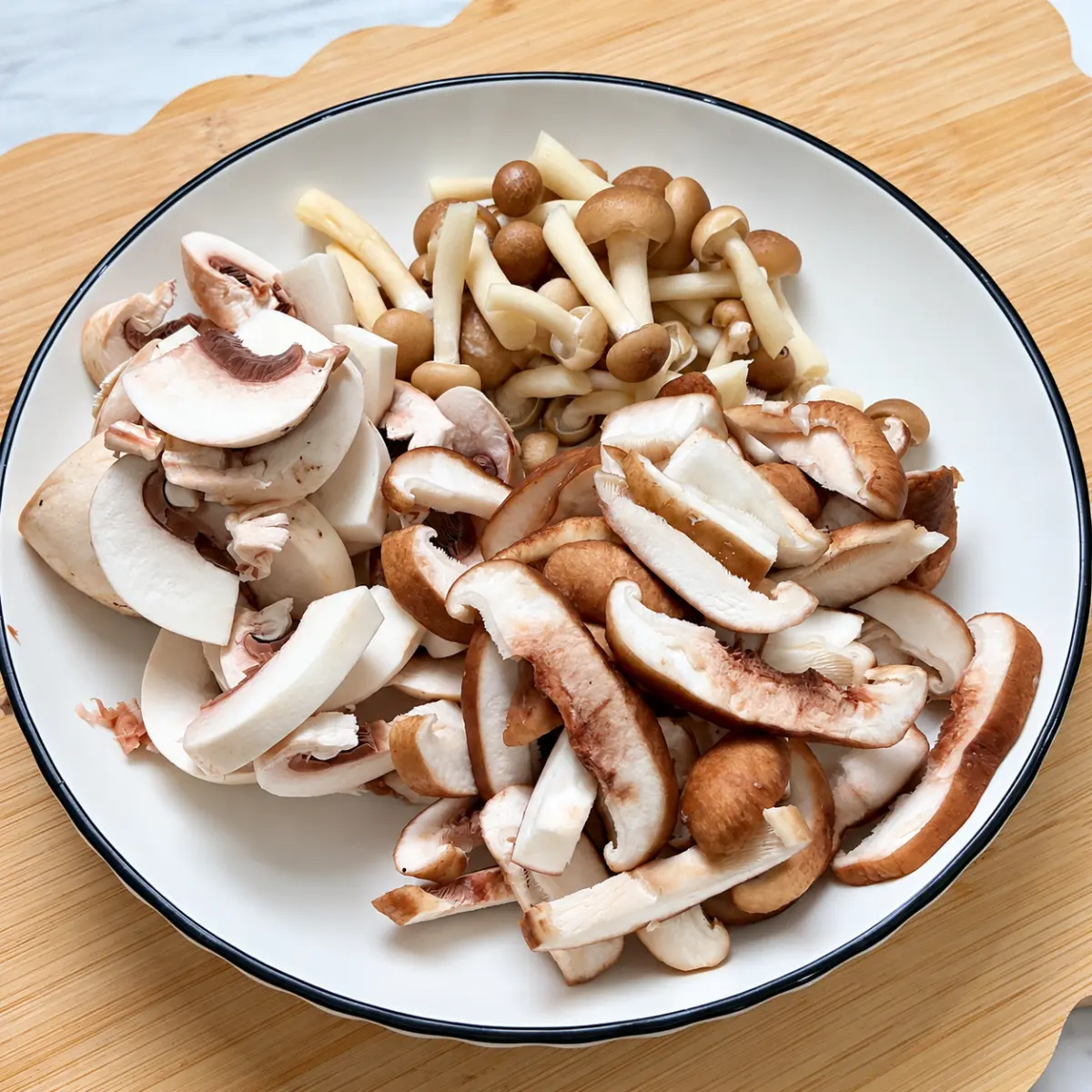 Sliced mixed mushrooms on a white plate with a black rim.